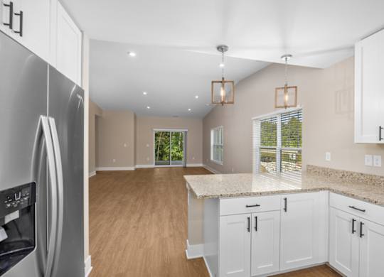 A kitchen with white cabinets and a refrigerator.