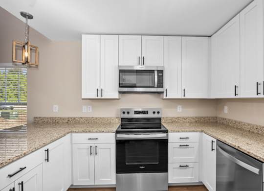 A kitchen with white cabinets and a granite countertop.