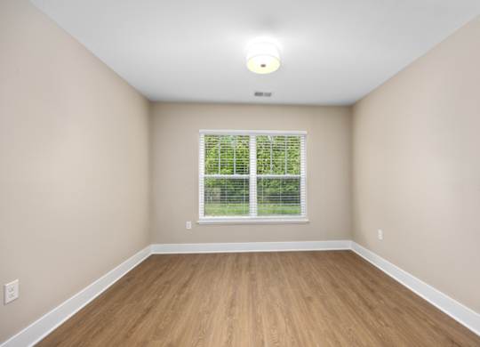 A room with a window and wooden flooring.