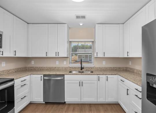 A kitchen with white cabinets and a granite countertop.