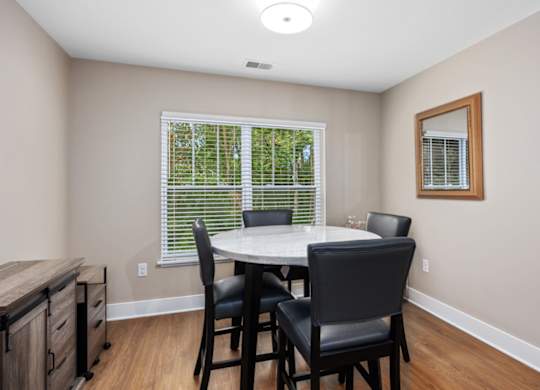 A dining room with a table and chairs.