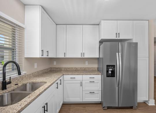 A kitchen with white cabinets and a stainless steel refrigerator.