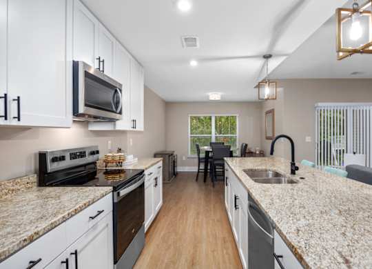A kitchen with granite countertops and white cabinets.