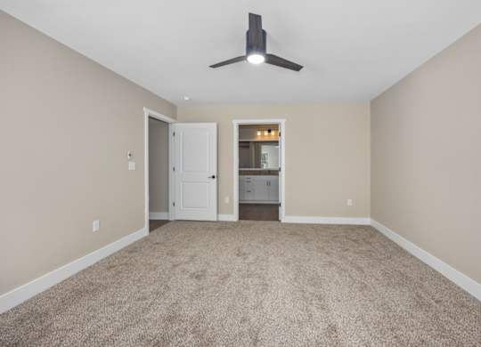 A room with a carpeted floor and a ceiling fan.
