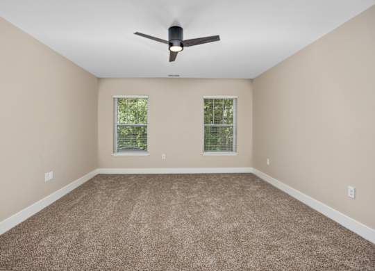 A room with a ceiling fan and carpeted floor.