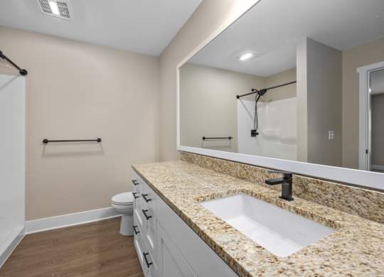 A bathroom with a granite countertop and a white sink.