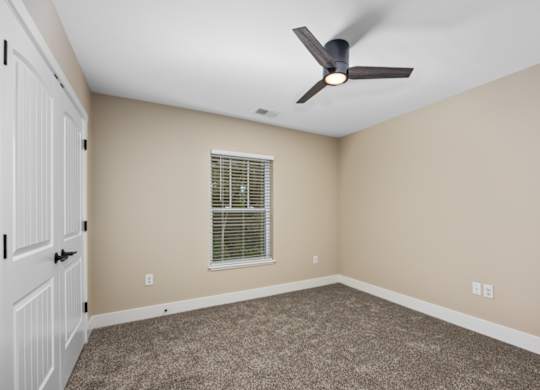 A room with a ceiling fan and a window with blinds.