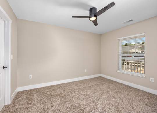 A room with a ceiling fan and a window with blinds.