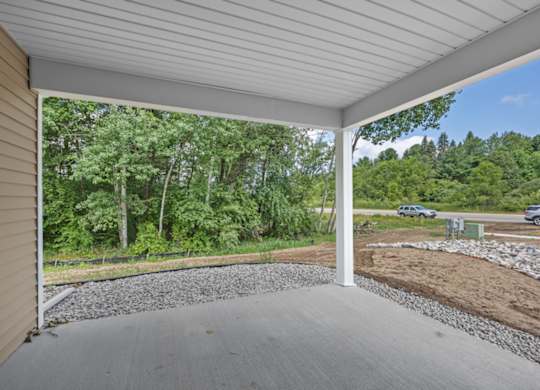 A covered porch with a gravel floor and a white ceiling.