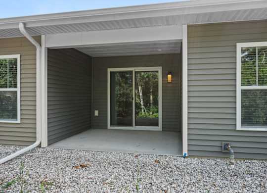 A house with a grey siding and a white roof with a glass door and window.