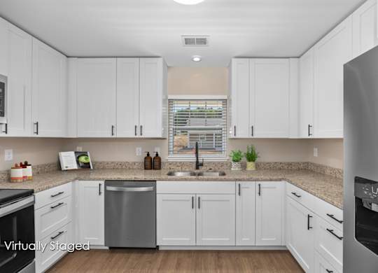A kitchen with white cabinets and a stainless steel dishwasher.