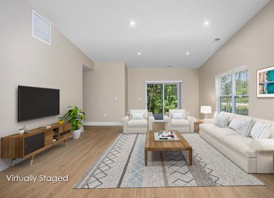 A living room with a white couch, a coffee table, and a flat screen TV.