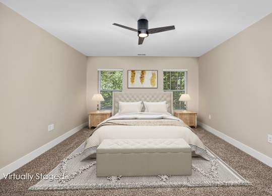 A bedroom with a large bed and a ceiling fan.