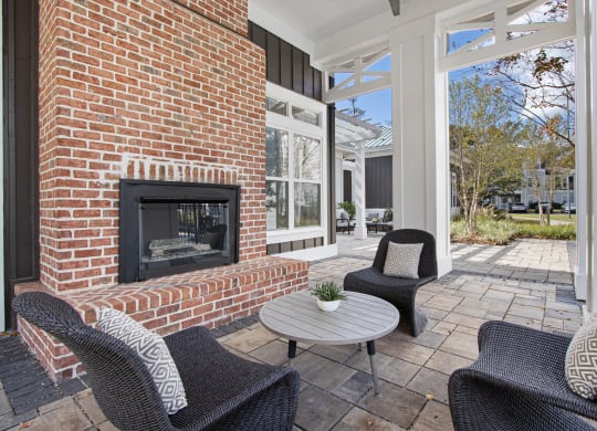 a patio with chairs and a brick fireplace