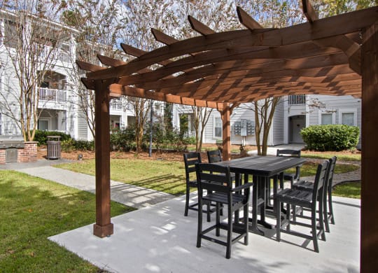 a patio with a table and chairs under a wooden pergola