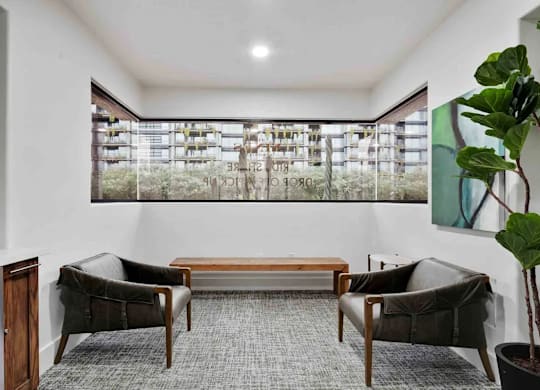 A room with a grey carpet and a large window with a view of a building.