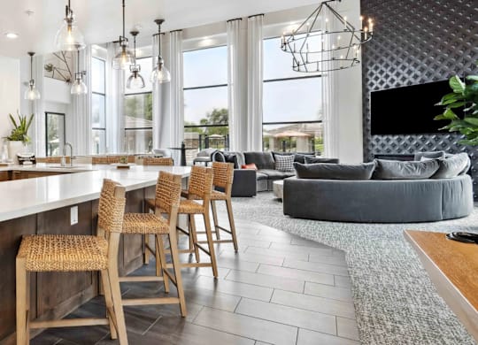 A modern kitchen with a bar area and a living room area with a grey couch.