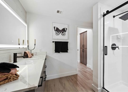 A bathroom with a white sink and a shower with a black railing.