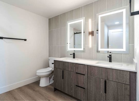A bathroom with a toilet, sink, and mirrors.