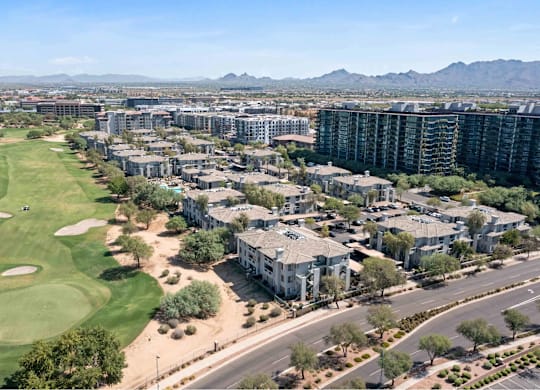 A golf course is surrounded by apartment buildings.