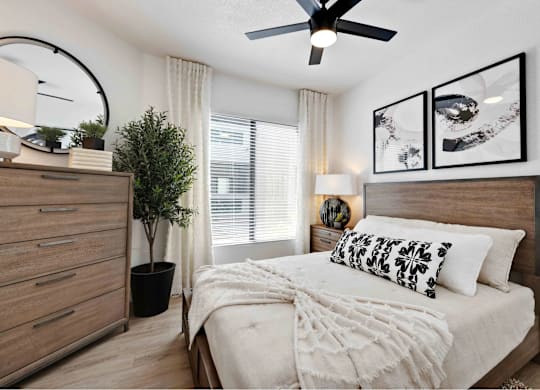 A bedroom with a bed, dresser, and ceiling fan.