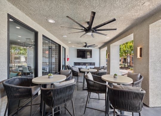 a patio with tables and chairs and a ceiling fan