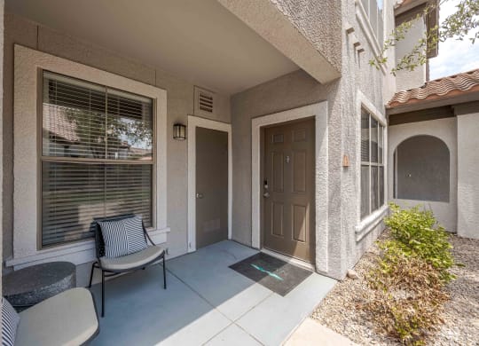 the front porch of a house with a chair and a door