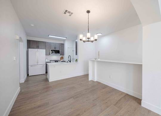 an open kitchen and living room with white walls and wood floors