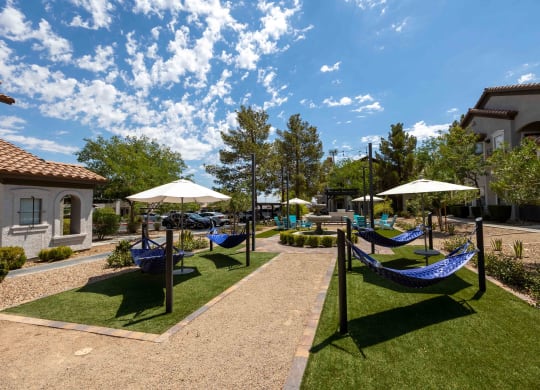 a patio with hammocks and umbrellas in a courtyard