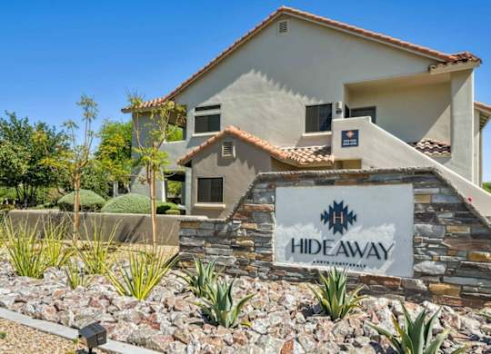 A house with a sign that says HIDEAWAY in front of it.