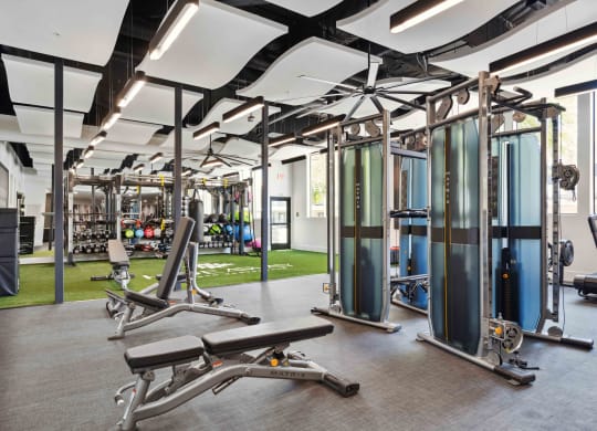 a spacious fitness center with benches at apartment community