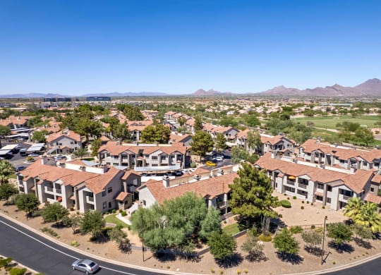 an aerial view of a neighborhood of houses with trees and mountains in the background