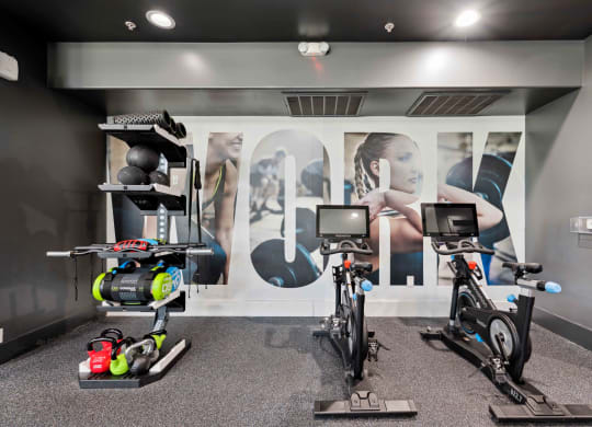 a gym with exercise equipment in front of a wall of ads