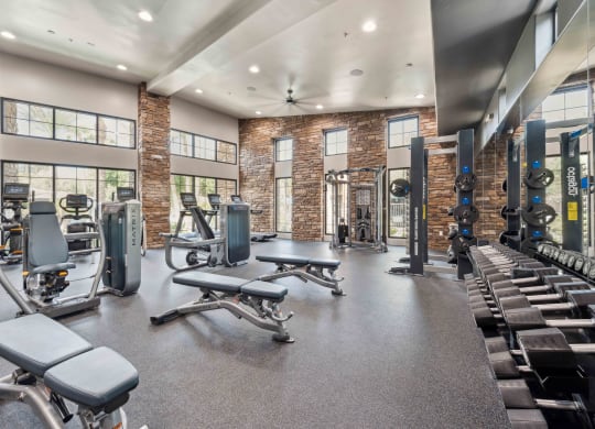 a gym with weights and cardio equipment and windows