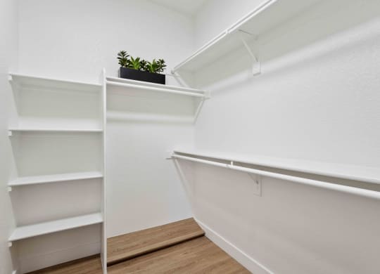 a walk in closet with white walls and shelves and