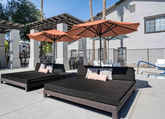 two couches with umbrellas in front of a building