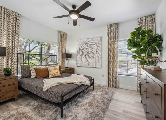 large bedroom at lazo apartments with ceiling fan and windows