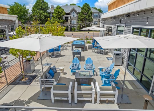 an outdoor patio with blue lounge chairs and white umbrellas