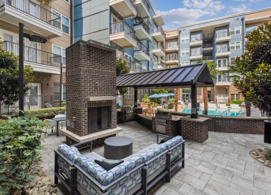 a patio with a fireplace and a pool in front of an apartment building