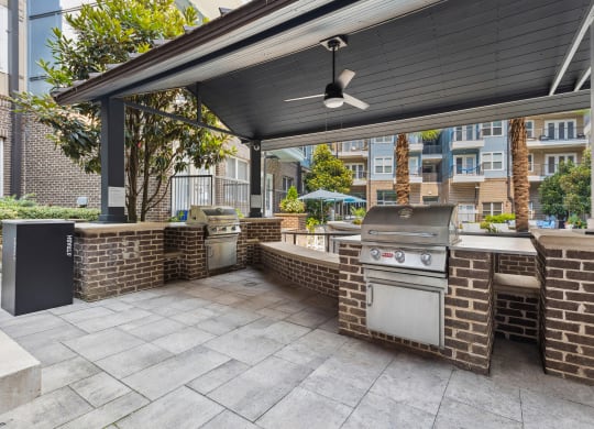 an outdoor kitchen with a grill and a ceiling fan