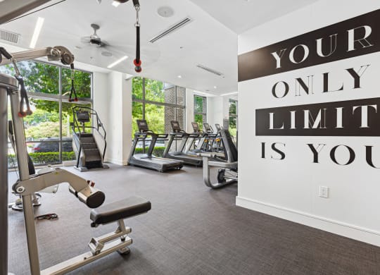 a gym with cardio equipment and a large sign that says your only limit is you