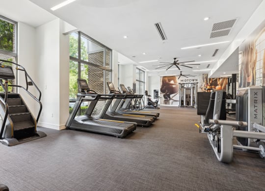 a room filled with cardio equipment and large windows