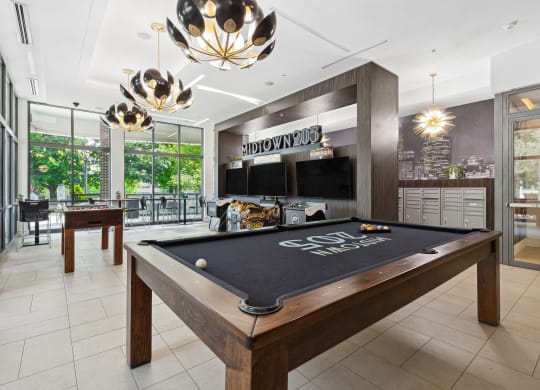 a games room with a pool table and two televisions