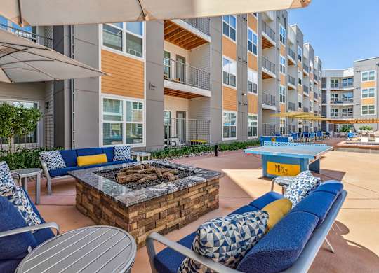 A patio with a fire pit and chairs.