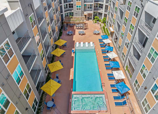 A large swimming pool surrounded by blue lounge chairs and yellow umbrellas.