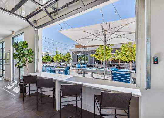 A patio with a table and chairs overlooking a pool.