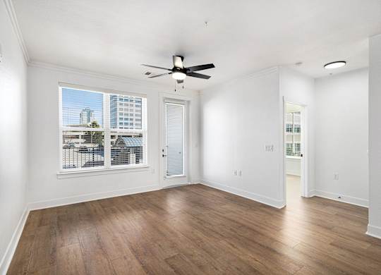 A room with a ceiling fan and a window overlooking a cityscape.