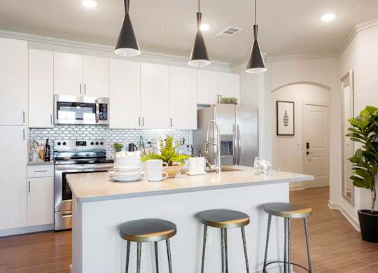 A kitchen with a white counter and bar stools.