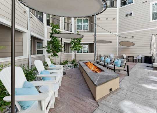 A patio with white chairs and a fire pit.