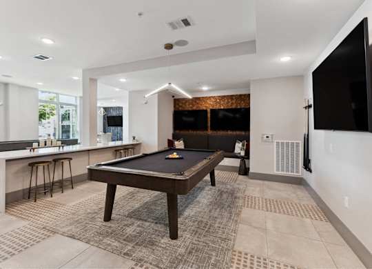 A room with a pool table and bar stools.